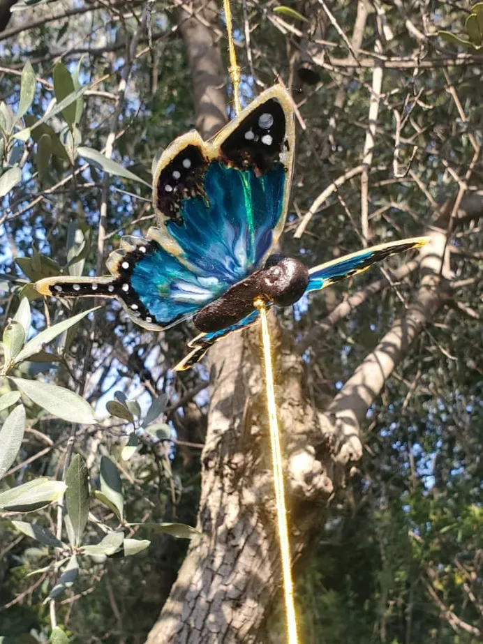 Teal butterfly on a stick in olive tree